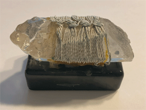 A succor punch quartz crystal wrapped with electrical wire.